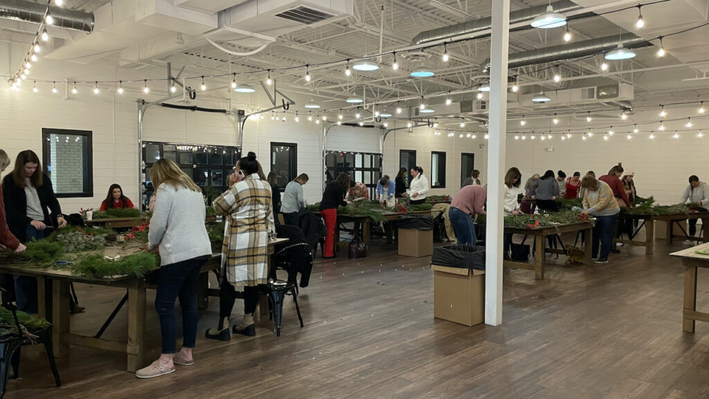 A group of people making wreaths at a holiday party at BASH in Carmel, Indiana