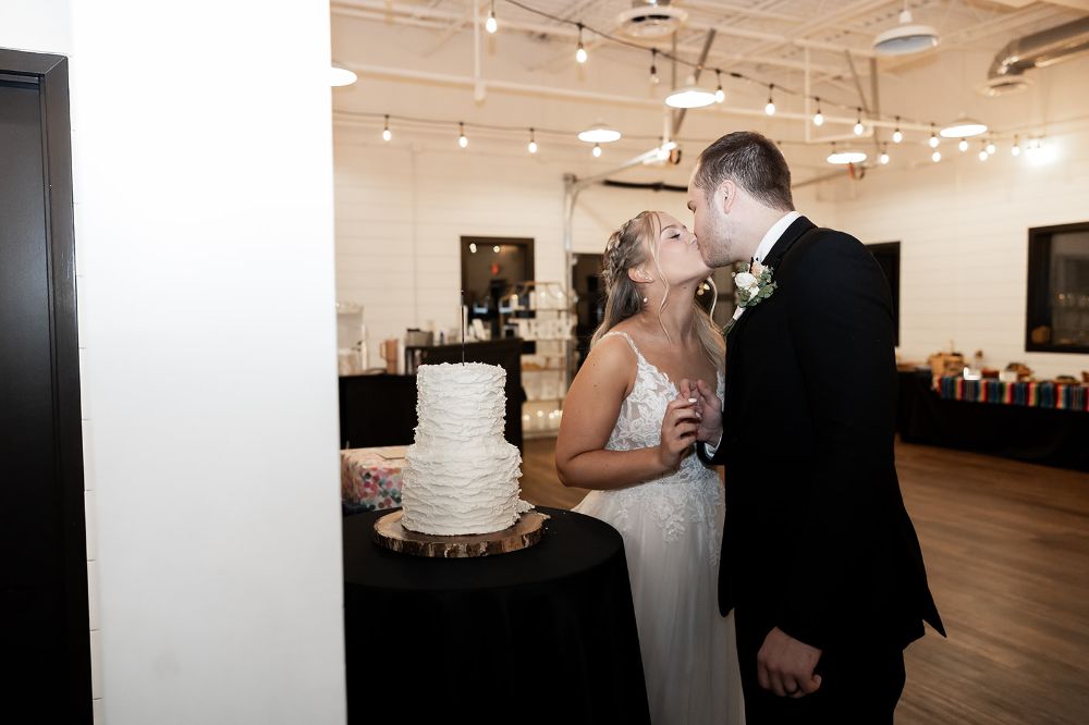 Bride and groom kissing in front of their wedding cake