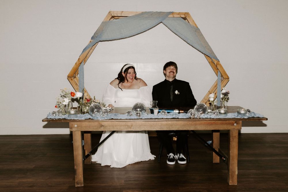 Bride and groom sitting at sweetheart table at BASH