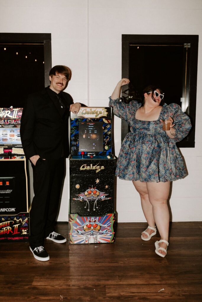 Bride and groom standing in front of arcade games at wedding at BASH