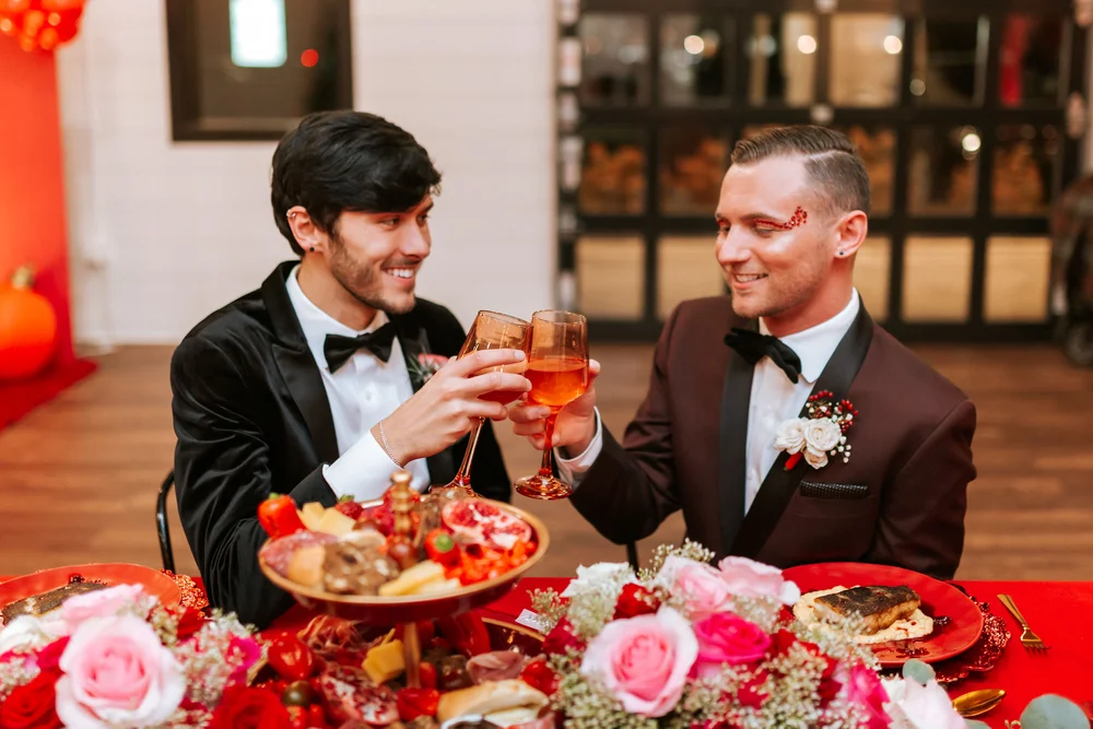 Two grooms cheers-ing on their wedding day at BASH