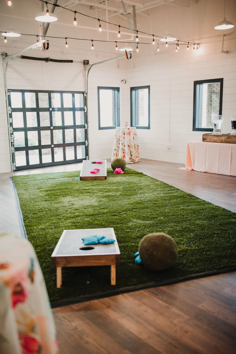 Game corner with a turf rug and cornhole set up for guests to play for holiday party.