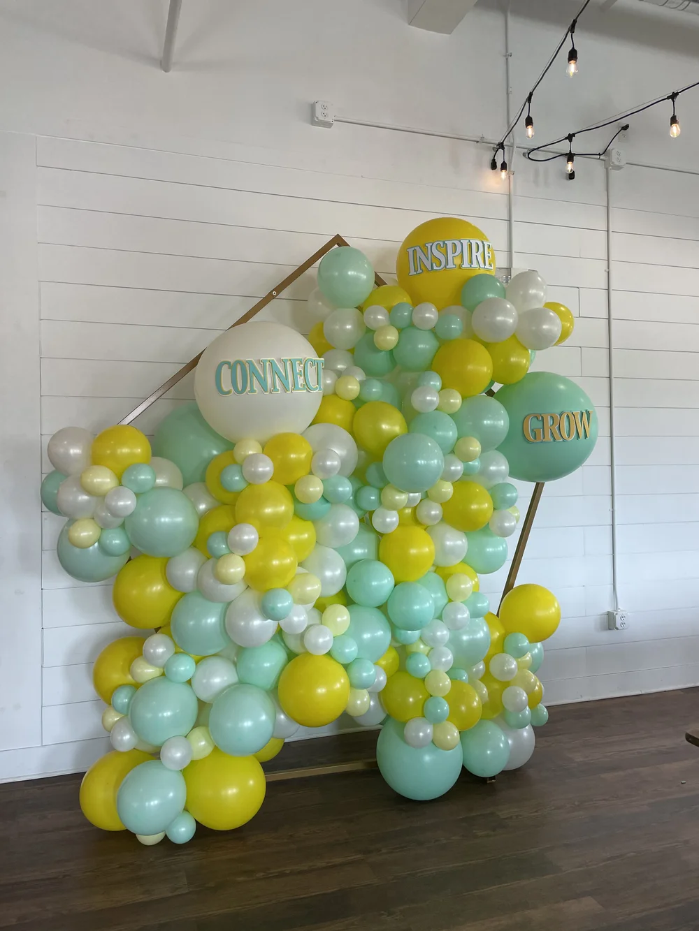 Photo booth backdrop full of balloons with a company's mantra on them for company party.