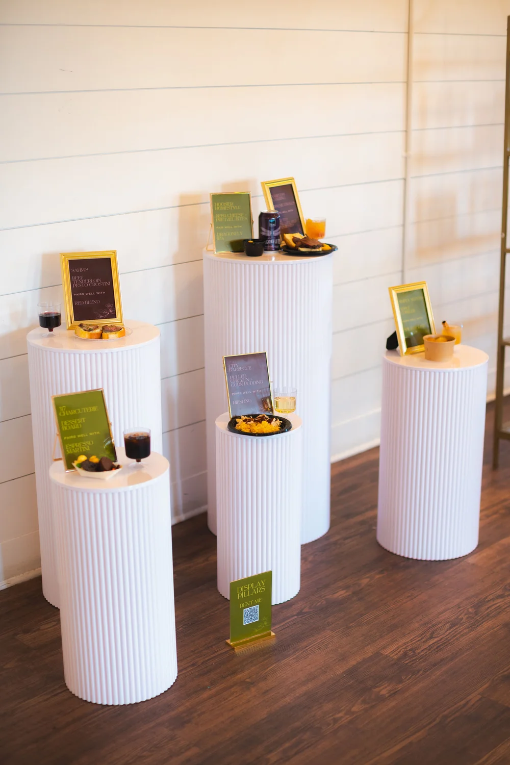 Appetizers and event signage displayed on white pillar stands at BASH Carmel wedding & event venue