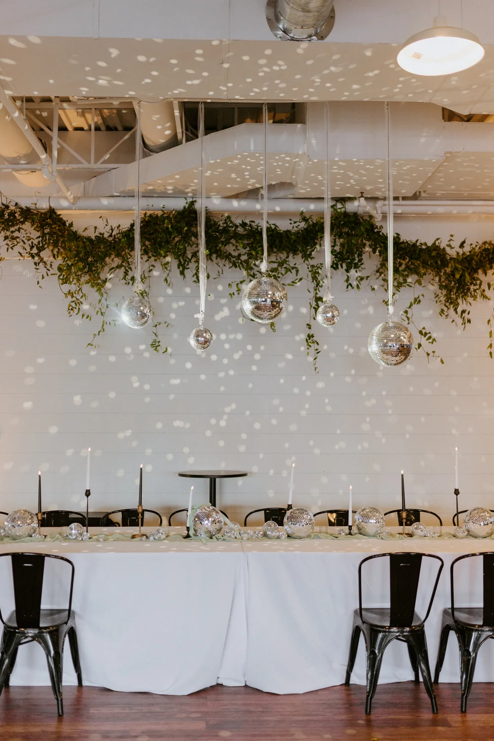 Head table setup for a wedding at BASH Carmel with disco balls and hanging greenery